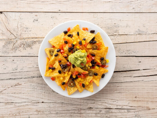 mexican-nachos-tortilla-chips-with-black-beans-guacamole-tomato-jalapeno-wooden-table